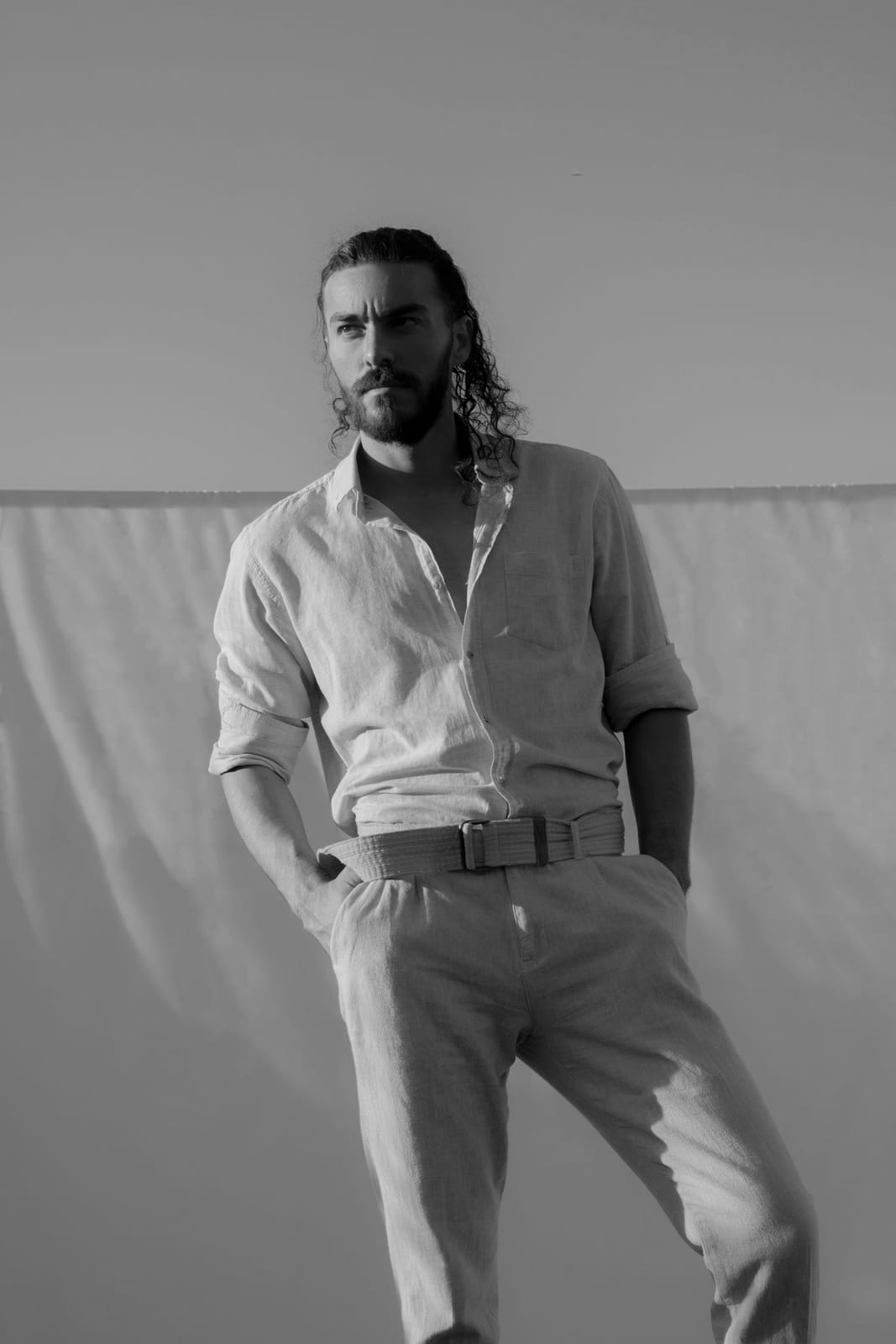 En blanco y negro, de cuerpo entero delante de las sábanas tendidas